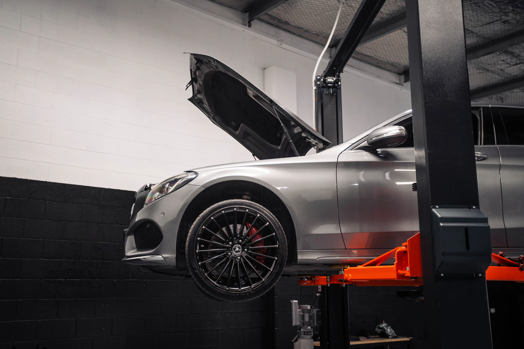 Silver car raised on a hydraulic lift with its bonnet open